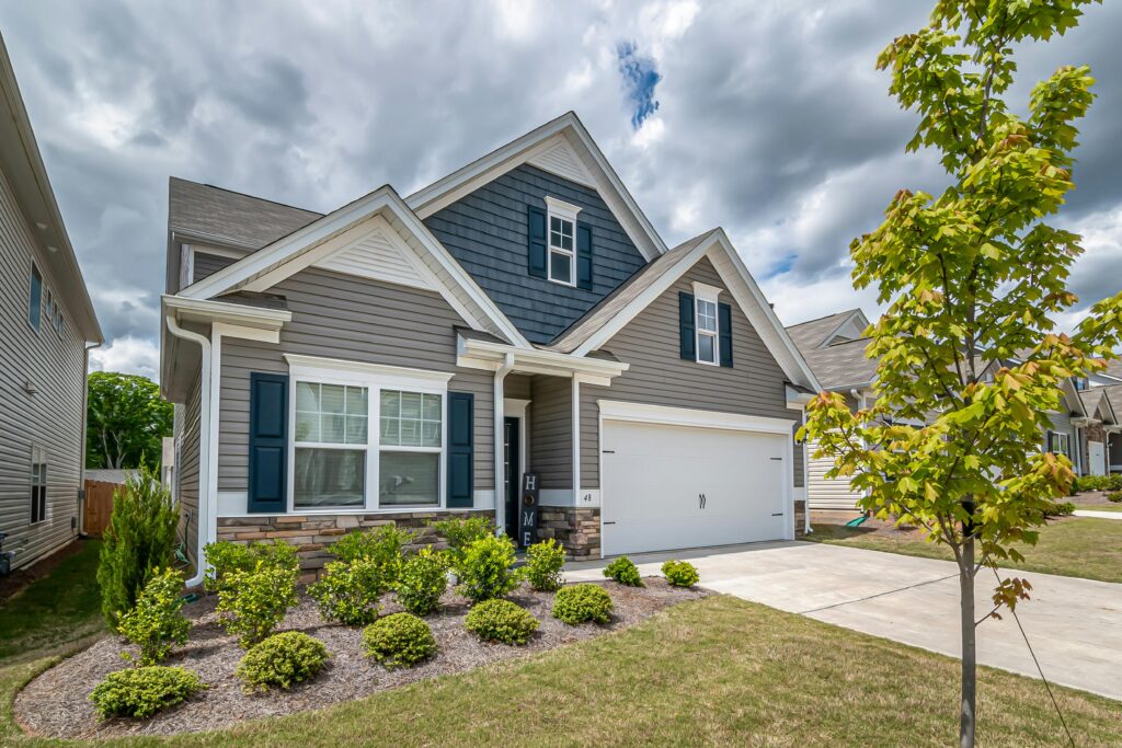 A beautiful suburban house with a manicured garden and cloudy sky, exemplifying modern architecture.