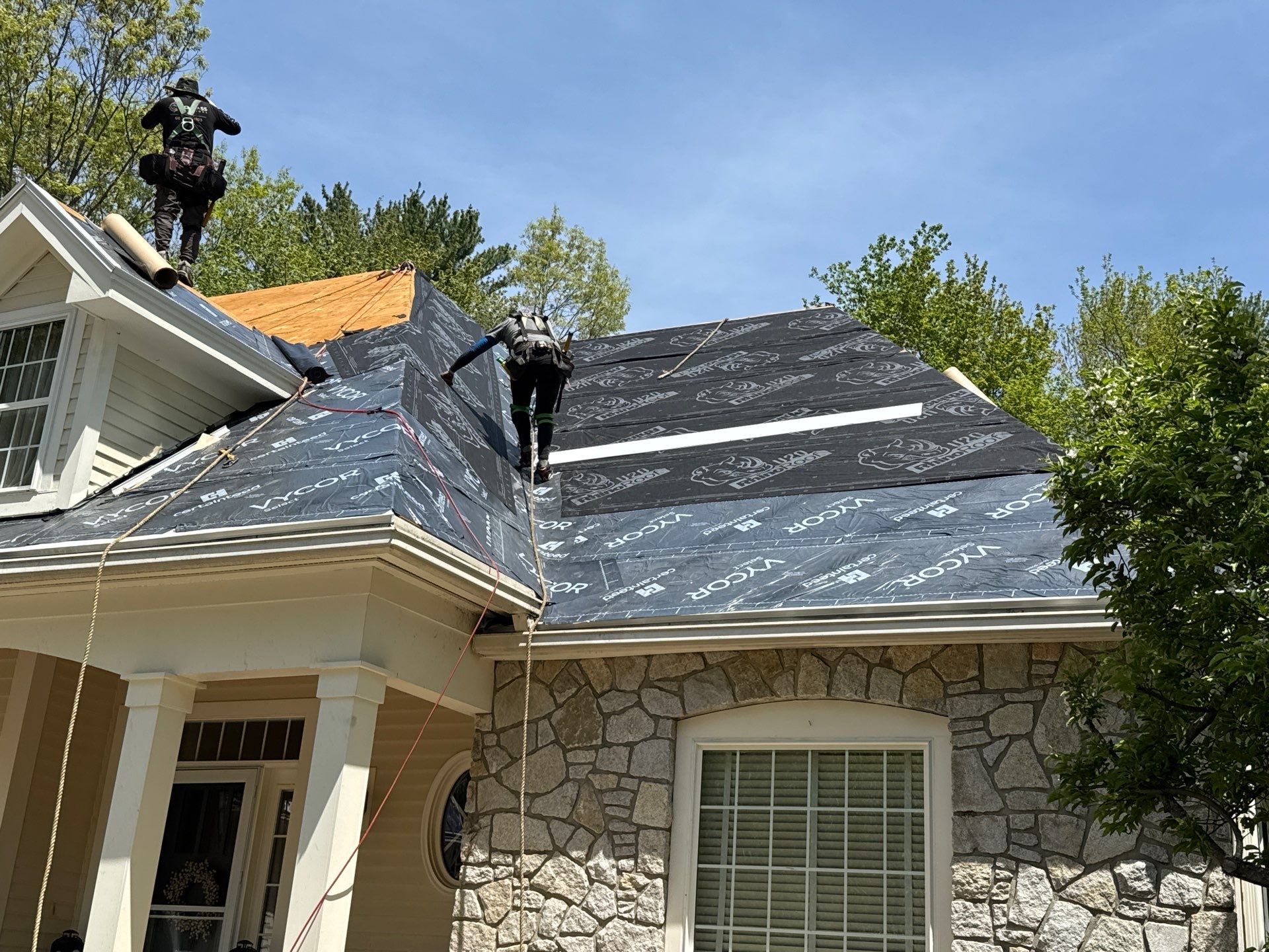 Synthetic underlayment rolled out over the roof deck during dry-in on an Exeter, NH roof replacement